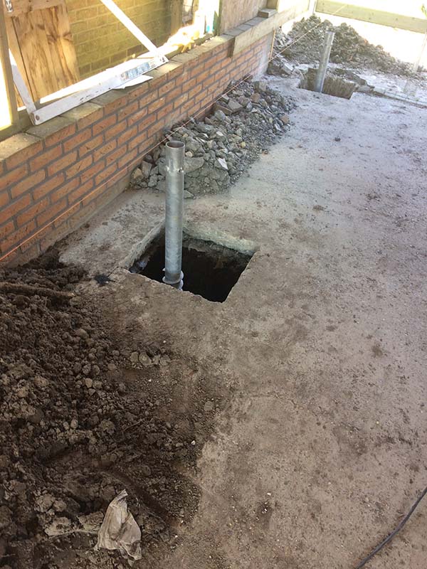 Handmatige schroefpaal installatie voor funderingsherstel in beperkte toegankelijke locatie