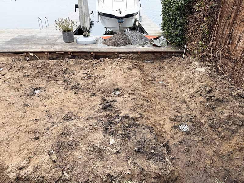 Vlonder fundering gereed voor afbouw na plaatsing schroefpalen in kleigrond, zichtbaar opgegraven terrein aan waterkant in Almere