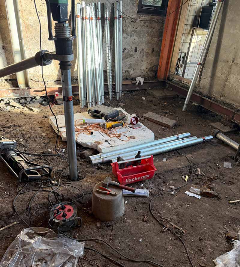 Krappe werkruimte in bijgebouw Rotterdam waar schroefpalen met handmachines zijn geplaatst zonder graafwerk.