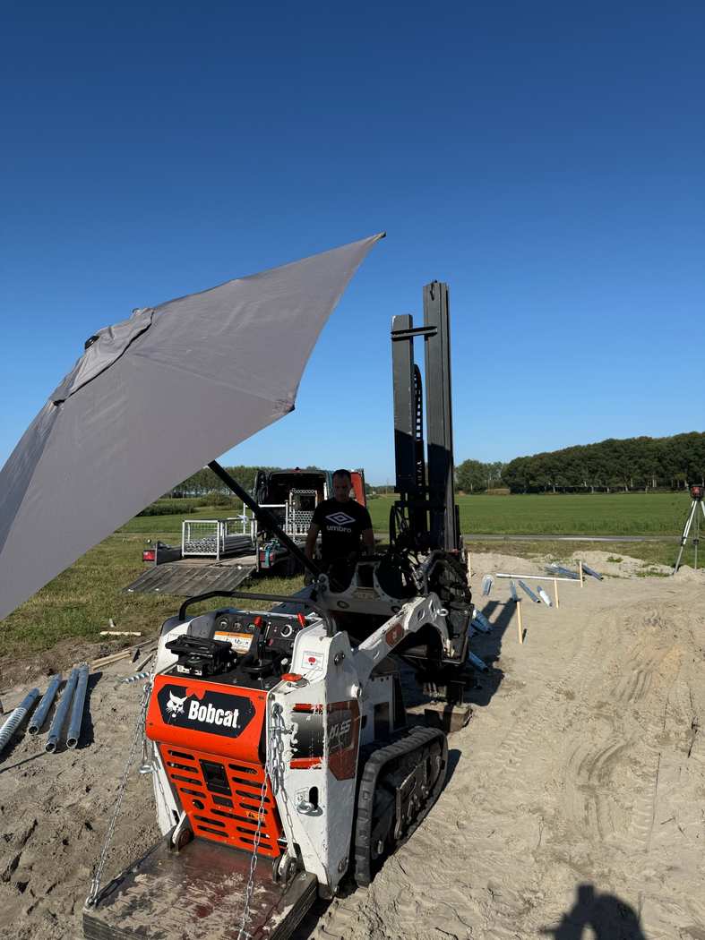 schroeffundering-tuinkamer-deest-machine.jpg Compacte rupsmachine van Van Aken met boorunit en schroefpalen klaar voor een tuinkamer in Deest